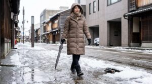 冬の金沢の濡れた雪道で、防水スノーブーツとダウンコートを着て歩く日本人女性